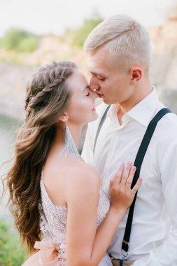 Zarif kıvırcık gelin ve damat göl arka plan üzerine açık havada. Damat ve gelin. gelinlik. Gelin düğün buket çiçek