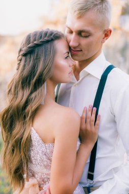 Zarif kıvırcık gelin ve damat göl arka plan üzerine açık havada. Damat ve gelin. gelinlik. Gelin düğün buket çiçek