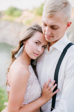 Zarif kıvırcık gelin ve damat göl arka plan üzerine açık havada. Damat ve gelin. gelinlik. Gelin düğün buket çiçek