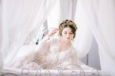 Güzel gelin portresi. Sabah gelin. Düğün sabah. Makyaj. Gelinle koniler ve sarı saçlar. Beyaz dantel sabahlık içinde kırılgan gelin