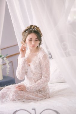 Güzel gelin portresi. Sabah gelin. Düğün sabah. Makyaj. Gelinle koniler ve sarı saçlar. Beyaz dantel sabahlık içinde kırılgan gelin