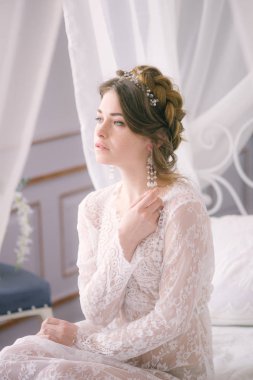 Güzel gelin portresi. Sabah gelin. Düğün sabah. Makyaj. Gelinle koniler ve sarı saçlar. Beyaz dantel sabahlık içinde kırılgan gelin