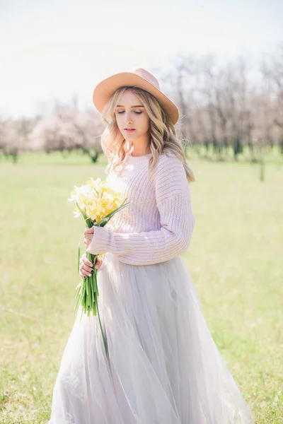 Genç Güzel Sarışın Kız Bir Şapka Bahar Bahçe Nergis Demetleri — Stok fotoğraf