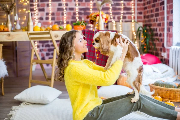 小さな犬とカボチャと黄色の葉で秋の装飾を持つスタジオで金髪の巻き毛を持つかわいい十代の女の子 人と犬 秋の気分 — ストック写真