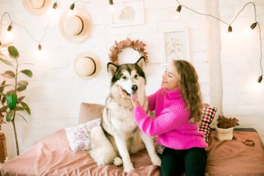 Evde sarı kıvırcık saçlı tatlı bir genç kız. Çatı katındaki yatakta, kocaman bir köpeğiyle. İnsanlar ve Köpekler.