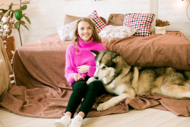 Evde sarı kıvırcık saçlı tatlı bir genç kız. Çatı katındaki yatakta, kocaman bir köpeğiyle. İnsanlar ve Köpekler.
