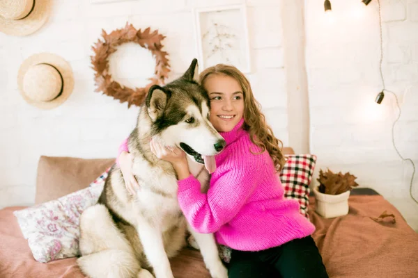 Evde sarı kıvırcık saçlı tatlı bir genç kız. Çatı katındaki yatakta, kocaman bir köpeğiyle. İnsanlar ve Köpekler.