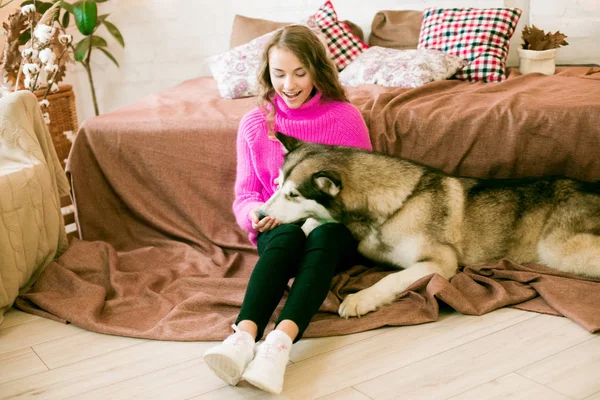 Evde sarı kıvırcık saçlı tatlı bir genç kız. Çatı katındaki yatakta, kocaman bir köpeğiyle. İnsanlar ve Köpekler.