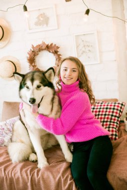 Evde sarı kıvırcık saçlı tatlı bir genç kız. Çatı katındaki yatakta, kocaman bir köpeğiyle. İnsanlar ve Köpekler.