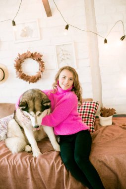 Evde sarı kıvırcık saçlı tatlı bir genç kız. Çatı katındaki yatakta, kocaman bir köpeğiyle. İnsanlar ve Köpekler.