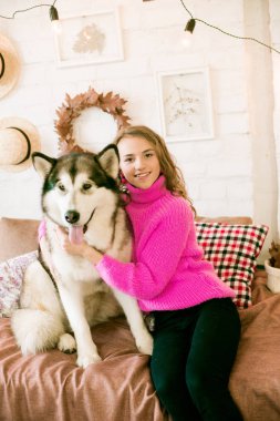 Evde sarı kıvırcık saçlı tatlı bir genç kız. Çatı katındaki yatakta, kocaman bir köpeğiyle. İnsanlar ve Köpekler.