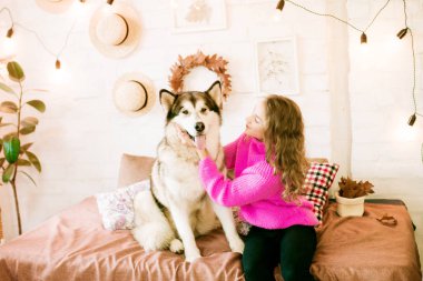 Evde sarı kıvırcık saçlı tatlı bir genç kız. Çatı katındaki yatakta, kocaman bir köpeğiyle. İnsanlar ve Köpekler.