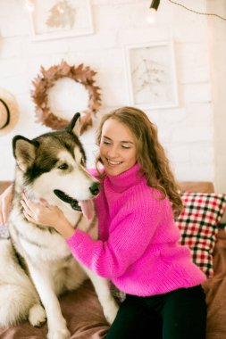 Evde sarı kıvırcık saçlı tatlı bir genç kız. Çatı katındaki yatakta, kocaman bir köpeğiyle. İnsanlar ve Köpekler.