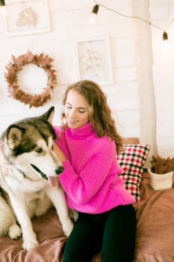 Evde sarı kıvırcık saçlı tatlı bir genç kız. Çatı katındaki yatakta, kocaman bir köpeğiyle. İnsanlar ve Köpekler.