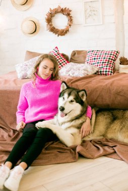 Evde sarı kıvırcık saçlı tatlı bir genç kız. Çatı katındaki yatakta, kocaman bir köpeğiyle. İnsanlar ve Köpekler.