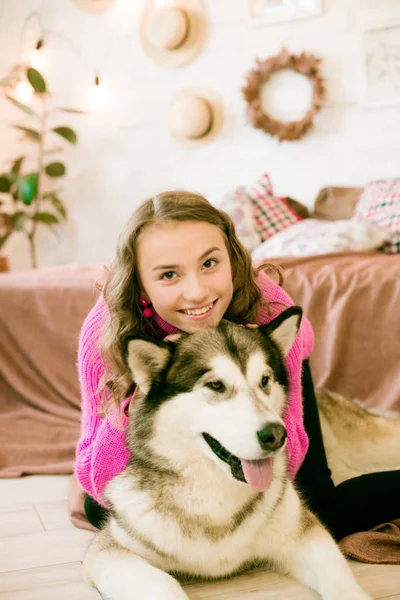 可爱的少女 在家里有一头金发卷曲的卷发 在阁楼的床上和一条大狗在一起 人与狗 — 图库照片