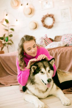 Evde sarı kıvırcık saçlı tatlı bir genç kız. Çatı katındaki yatakta, kocaman bir köpeğiyle. İnsanlar ve Köpekler.