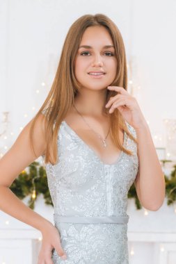 Sarışın ve akşam makyajlı çekici bir genç kız Noel ağacının yanında hediyeler ve çelenklerle. Yeni Yıl 2020.