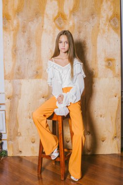 Sarışın ve akşam makyajlı, eski moda pantolonları ve şifonlu bluzu olan çekici bir genç kız. 