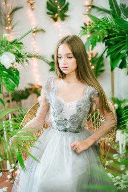 Sarışın ve akşam makyajlı çekici genç kız tropik yeşillikler, beyaz orkideler, güller ve zambaklar arasında romantik bir elbise giyiyor. Güzellik ve moda