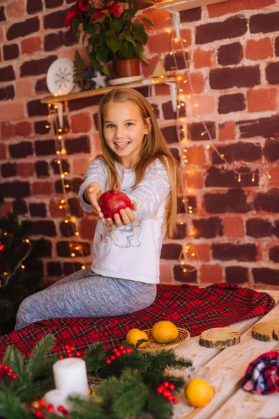 可爱的小女孩穿着睡衣 在厨房的桌子旁边玩乐 桌上有姜饼饼干 家里有橘子 房间里装饰着圣诞花环和针头 圣诞气氛 — 图库照片