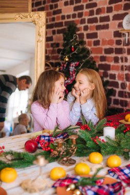 Pijamalı şirin kız kardeşler mutfaktaki masada zencefilli kurabiyelerle, evde mandalinalarla Noel çelenkleri ve iğneleriyle eğleniyorlar. - Evet. Noel havası