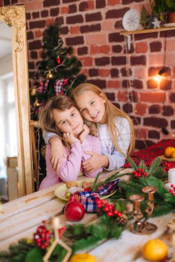 Pijamalı şirin kız kardeşler mutfaktaki masada zencefilli kurabiyelerle, evde mandalinalarla Noel çelenkleri ve iğneleriyle eğleniyorlar. - Evet. Noel havası
