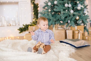 Noel ağacı ve çelenk ve hediyelerle süslenmiş şöminenin yanında tatlı bir çocuk. Noel havası