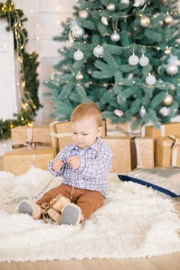 Noel ağacı ve çelenk ve hediyelerle süslenmiş şöminenin yanında tatlı bir çocuk. Noel havası