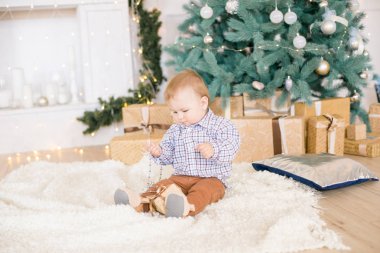 Noel ağacı ve çelenk ve hediyelerle süslenmiş şöminenin yanında tatlı bir çocuk. Noel havası