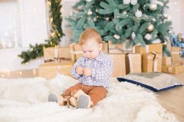 Noel ağacı ve çelenk ve hediyelerle süslenmiş şöminenin yanında tatlı bir çocuk. Noel havası