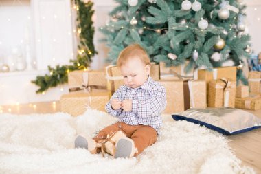 Noel ağacı ve çelenk ve hediyelerle süslenmiş şöminenin yanında tatlı bir çocuk. Noel havası