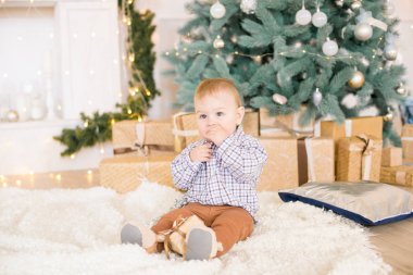 Noel ağacı ve çelenk ve hediyelerle süslenmiş şöminenin yanında tatlı bir çocuk. Noel havası