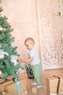 Noel ağacı ve çelenk ve hediyelerle süslenmiş şöminenin yanında tatlı bir çocuk. Noel havası