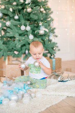 Noel ağacı ve çelenk ve hediyelerle süslenmiş şöminenin yanında tatlı bir çocuk. Noel havası