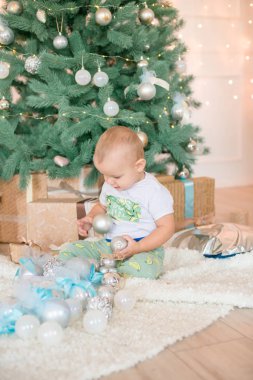 Noel ağacı ve çelenk ve hediyelerle süslenmiş şöminenin yanında tatlı bir çocuk. Noel havası