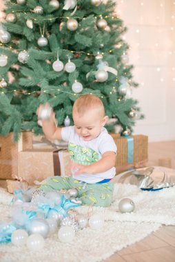 Noel ağacı ve çelenk ve hediyelerle süslenmiş şöminenin yanında tatlı bir çocuk. Noel havası