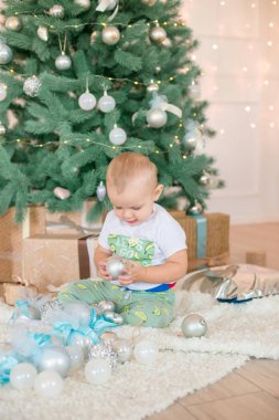 Noel ağacı ve çelenk ve hediyelerle süslenmiş şöminenin yanında tatlı bir çocuk. Noel havası