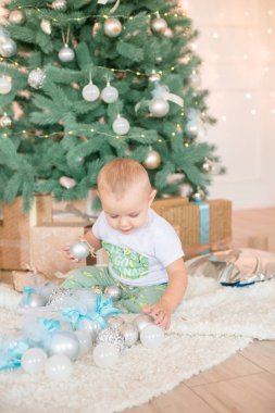 Noel ağacı ve çelenk ve hediyelerle süslenmiş şöminenin yanında tatlı bir çocuk. Noel havası
