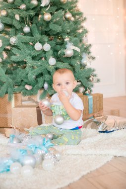 Noel ağacı ve çelenk ve hediyelerle süslenmiş şöminenin yanında tatlı bir çocuk. Noel havası