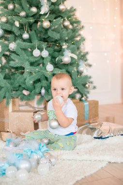 Noel ağacı ve çelenk ve hediyelerle süslenmiş şöminenin yanında tatlı bir çocuk. Noel havası