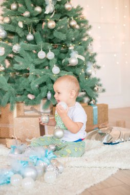 Noel ağacı ve çelenk ve hediyelerle süslenmiş şöminenin yanında tatlı bir çocuk. Noel havası