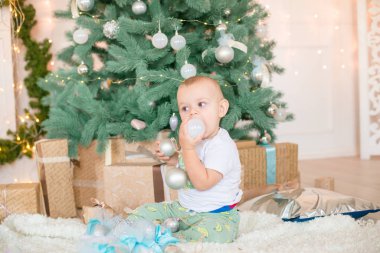 Noel ağacı ve çelenk ve hediyelerle süslenmiş şöminenin yanında tatlı bir çocuk. Noel havası