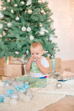 Noel ağacı ve çelenk ve hediyelerle süslenmiş şöminenin yanında tatlı bir çocuk. Noel havası