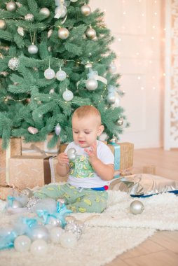 Noel ağacı ve çelenk ve hediyelerle süslenmiş şöminenin yanında tatlı bir çocuk. Noel havası