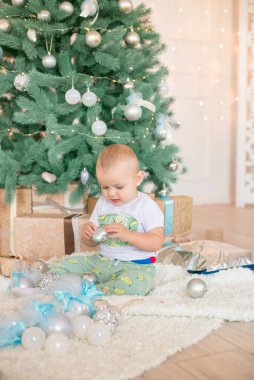 Noel ağacı ve çelenk ve hediyelerle süslenmiş şöminenin yanında tatlı bir çocuk. Noel havası