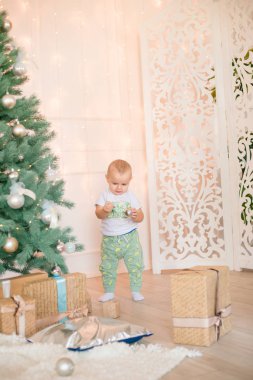 Noel ağacı ve çelenk ve hediyelerle süslenmiş şöminenin yanında tatlı bir çocuk. Noel havası