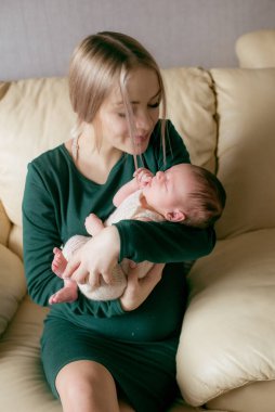 Evinde kucağında bir bebekle güzel sarı saçlı mamaso. Mutlu annelik