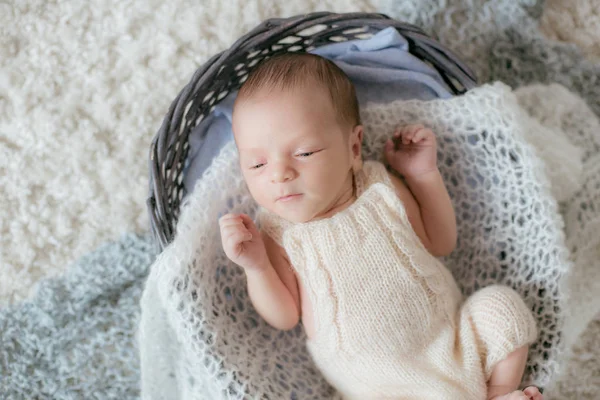 可爱的小宝宝躺在家里的一个白色毛绒绒地毯上 篮子里有柔软的针织斜纹棉布 母性快乐 — 图库照片