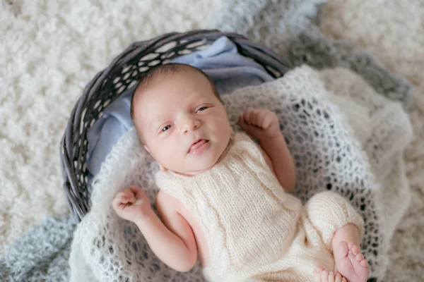 かわいい赤ちゃんは 柔らかいニットのプレッドを持つウィッカーバスケットの白いふわふわのカーペットの上に家にあります 幸せな母親 — ストック写真